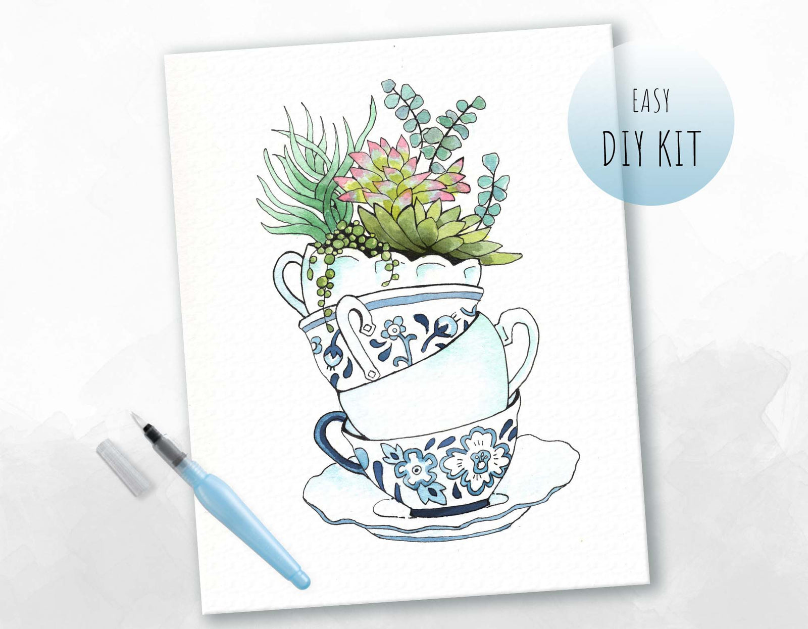 A DIY watercolor kit promotional image featuring a completed art piece of a teacup with Chinoiserie techniques and succulents, along with a pen and brush for the kit.